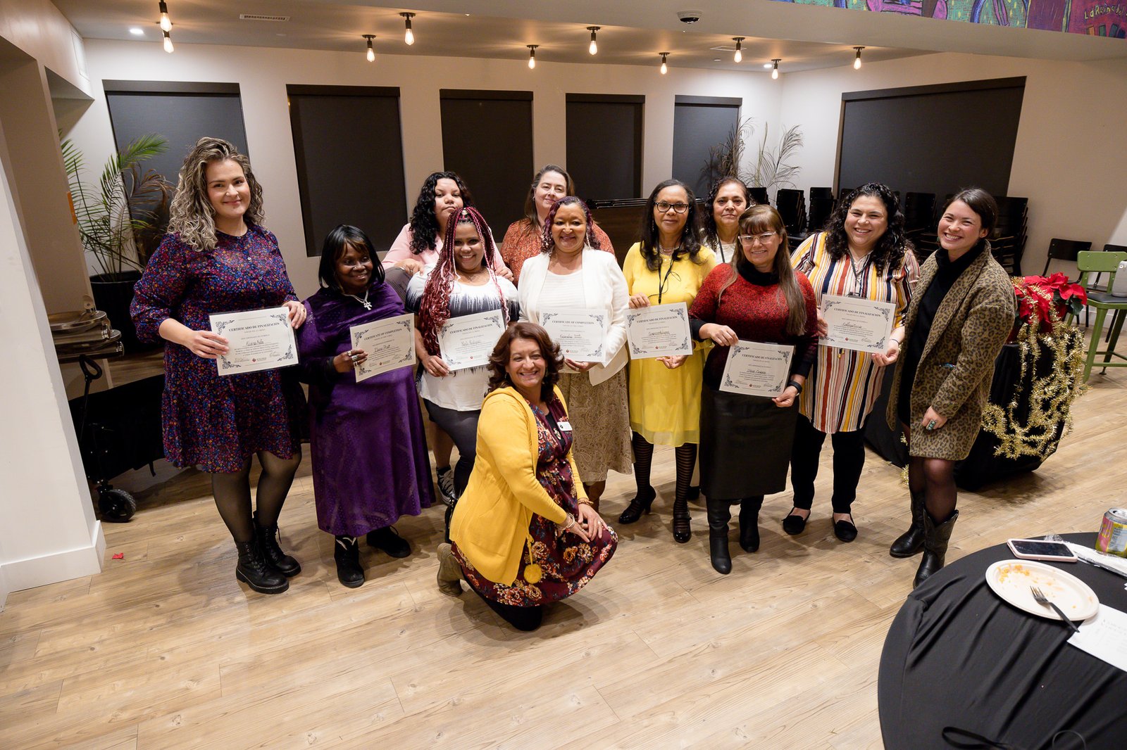 Ten of the storytellers and two staff members take a group photo smiling and holding certificates of completion.