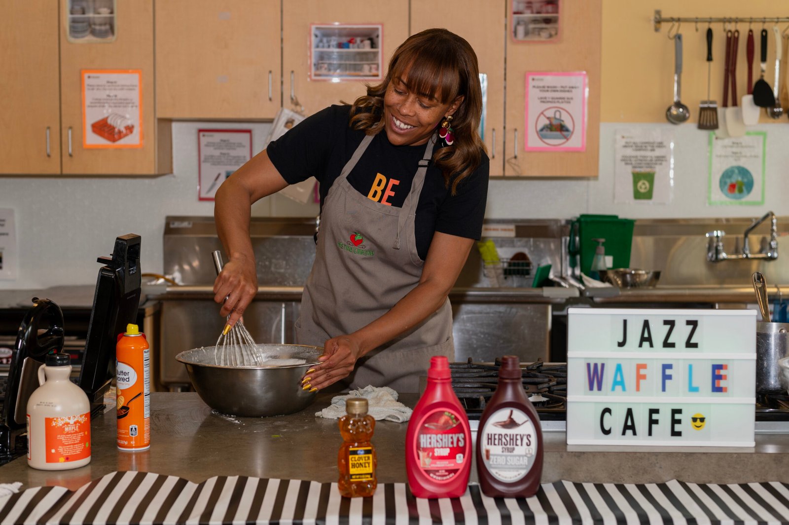 Danette smiles as she whisks waffle batter in a large bowl. 