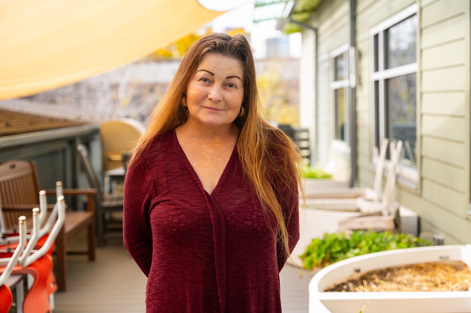 Laurie Ann stands on Metro Caring's patio, smiling lightly at the camera. 